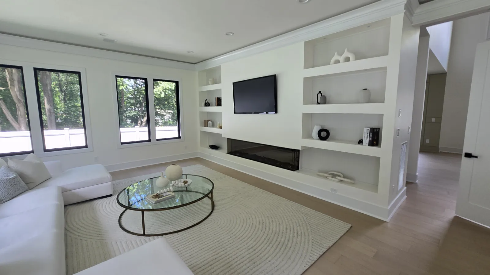 Wall-mounted TV over a linear fireplace with custom built-in shelving