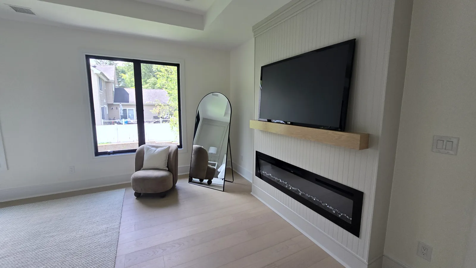 Flush wall-mounted TV above a fireplace with hidden wiring
